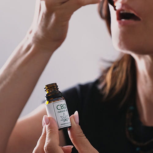 Woman using hemp CBD oil dropper