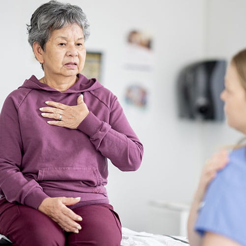 Woman demonstrating chest discomfort to a medical professional