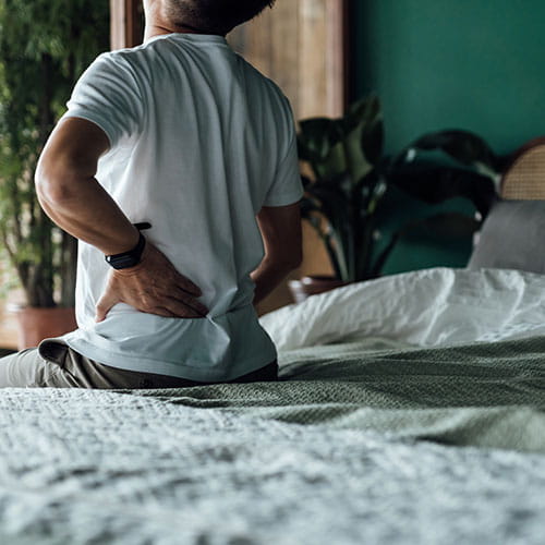 Man with back pain sitting on a bed