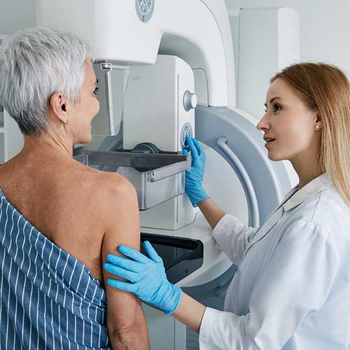 Senior woman having mammography scan at hospital with medical technician. Mammography procedure, breast cancer prevention