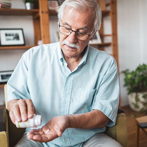 Man pouring pills into hand