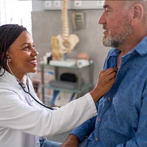Female doctor listening to male senior patient's heartbeat at doctor's office