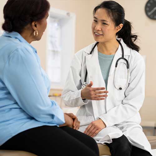 A senior woman of African descent listens to her doctor explain the outcome of her most recent tests.