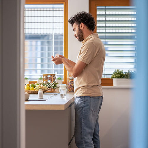 Young Man Taking Medicine With Water At Home