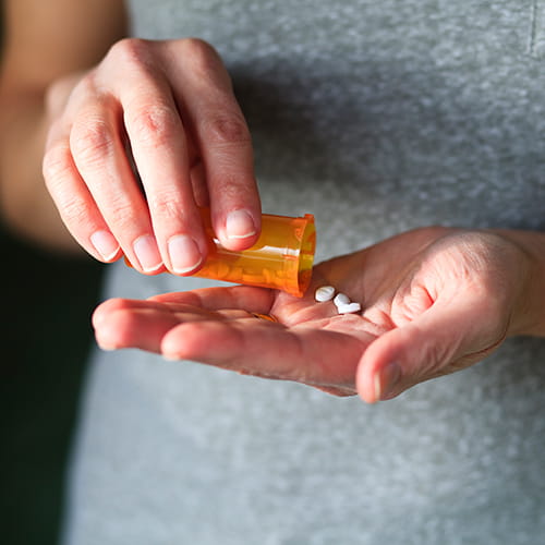 woman pouring out pills
