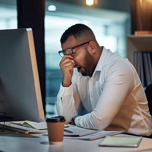 man looking tired sitting at a desk