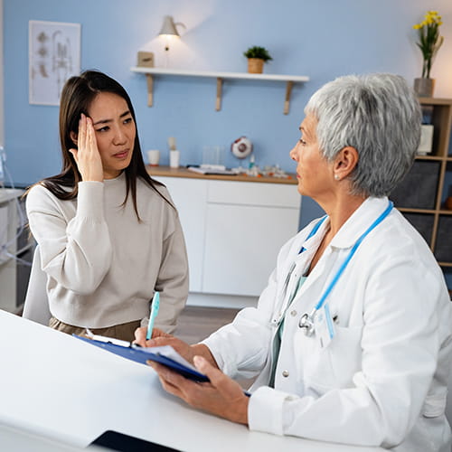 woman holding her head talking to doctor