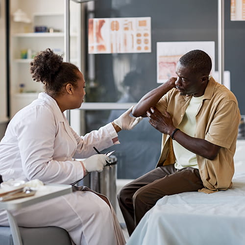 doctor examining mans elbow