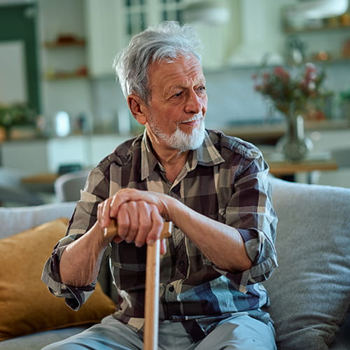 older man sitting with a cane
